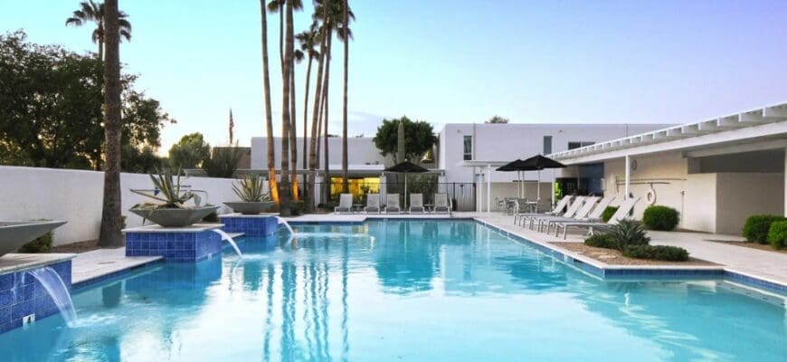 Outdoor resort-style pool at Winfield of Scottsdale with lounge seating, water features, and surrounding palm trees